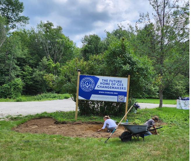 Clearing ground beside the campus sign.