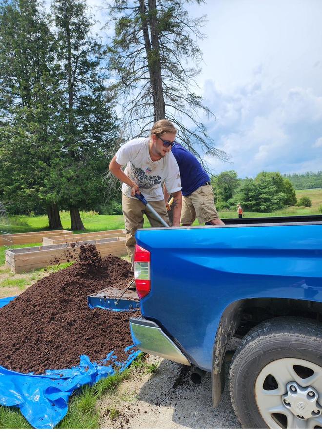 Shovelling mulch from the back of a truck.